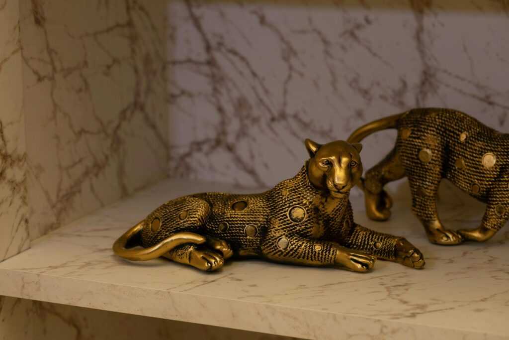 Stylish golden leopard sculptures on a marble shelf, ideal for decor enthusiasts.