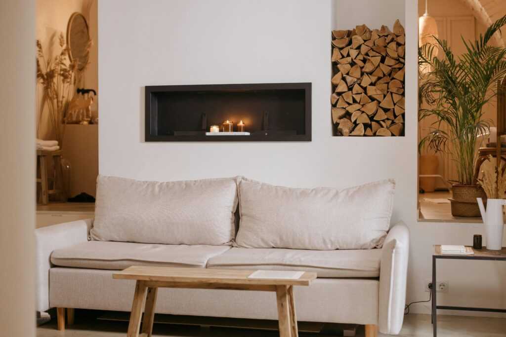 A serene minimalist living room featuring a clean lined sofa, wooden accents, and ambient candles.